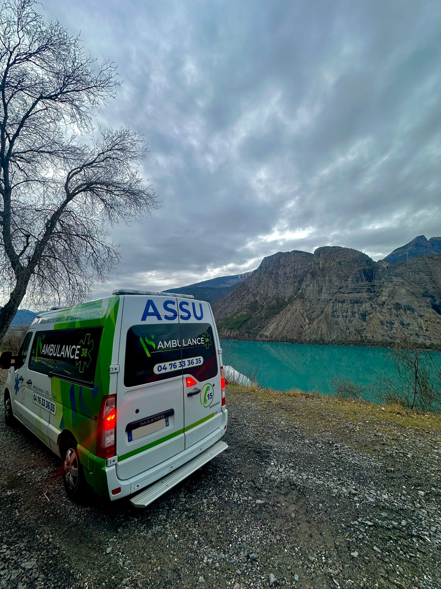 Une ambulance devant un lac et des falaises