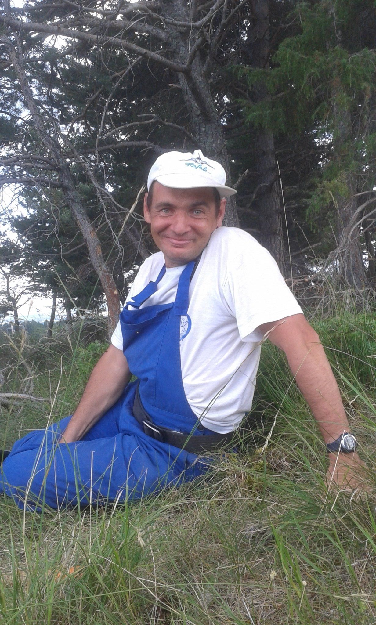 Photo d'un homme avec un bleu de travail assis dans l'herbe