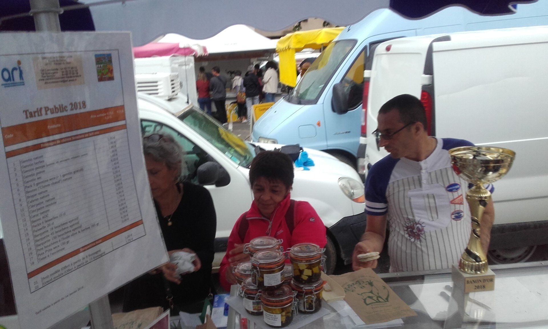Photo de trois personnes sur le stand de fromage d'un marché