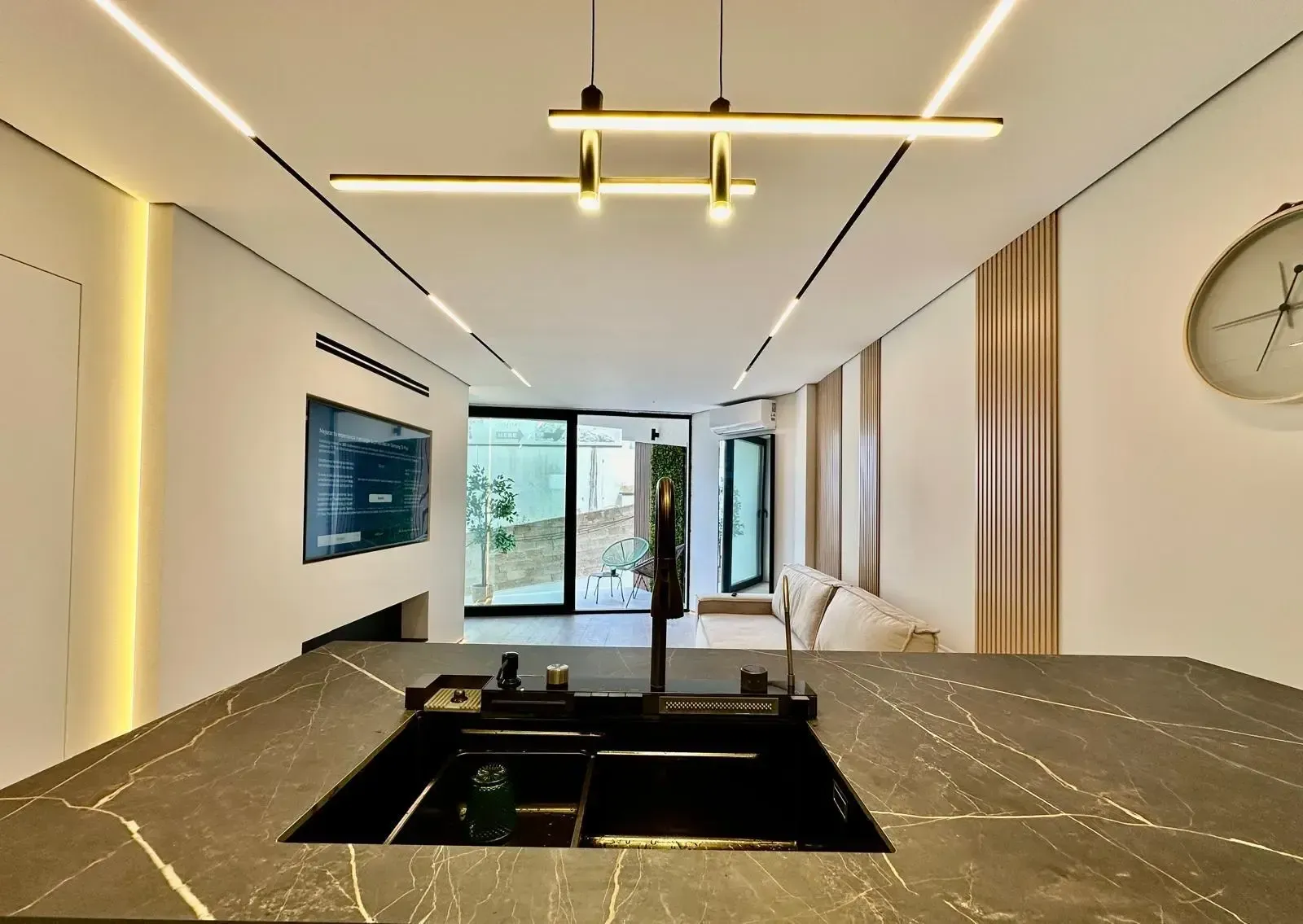 Cocina moderna de planta abierta con isla negra, detalles en madera y ventanales del suelo al techo.