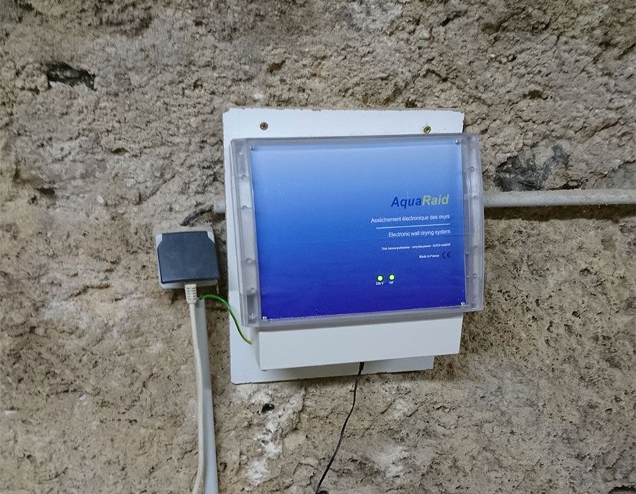 Dispositif mural bleu avec câbles sur un mur en pierre brute