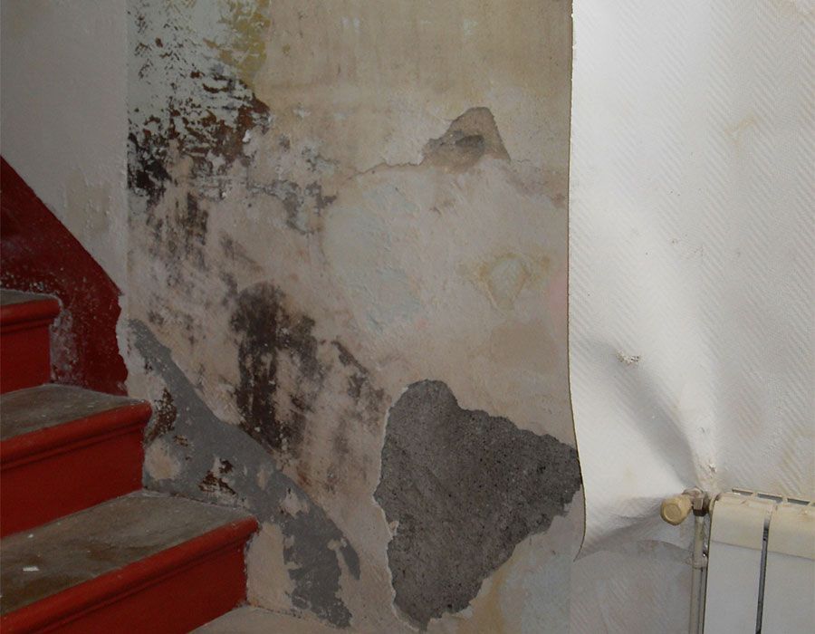 Mur abîmé et délavé à côté d'un escalier rouge, avec un radiateur à droite