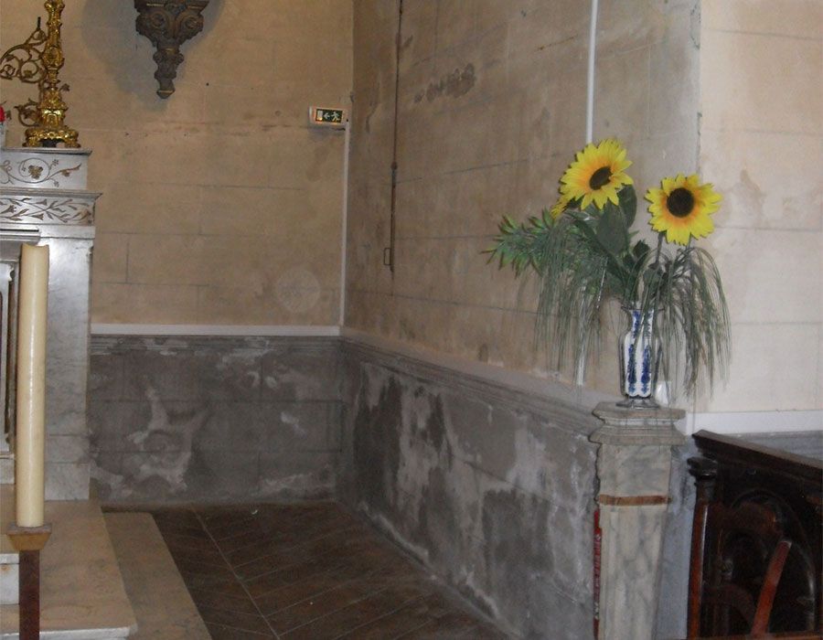 Des tournesols dans un vase sur un rebord en pierre dans un couloir intérieur faiblement éclairé