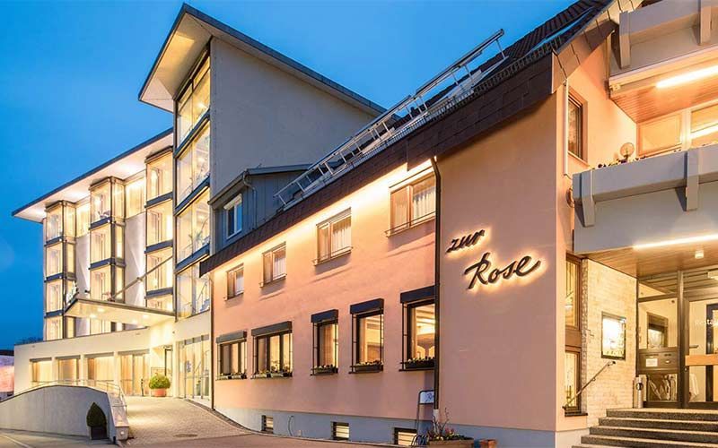 Ein großes Gebäude mit vielen Fenstern ist nachts beleuchtet. Der Eingang des Hotels.