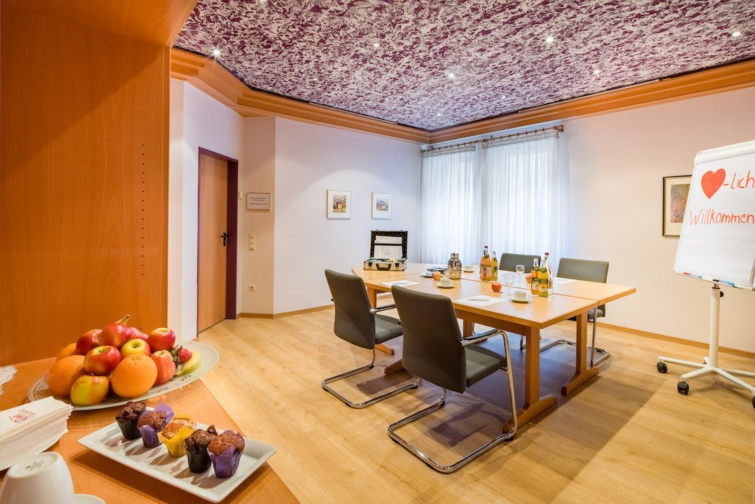 Ein Wohnzimmer mit einem Tisch und Stühlen und einem Obstteller.
