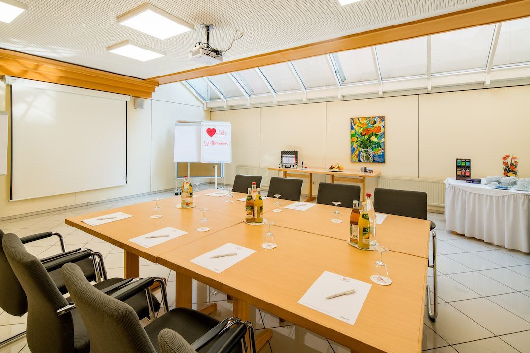 Ein Konferenzraum mit einem langen Tisch, Stühlen und einer Tafel.