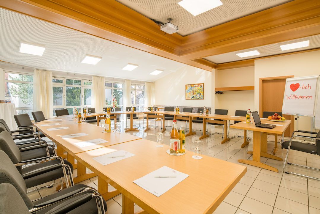 Ein Konferenzraum mit einem langen Tisch, Stühlen und einer Tafel.