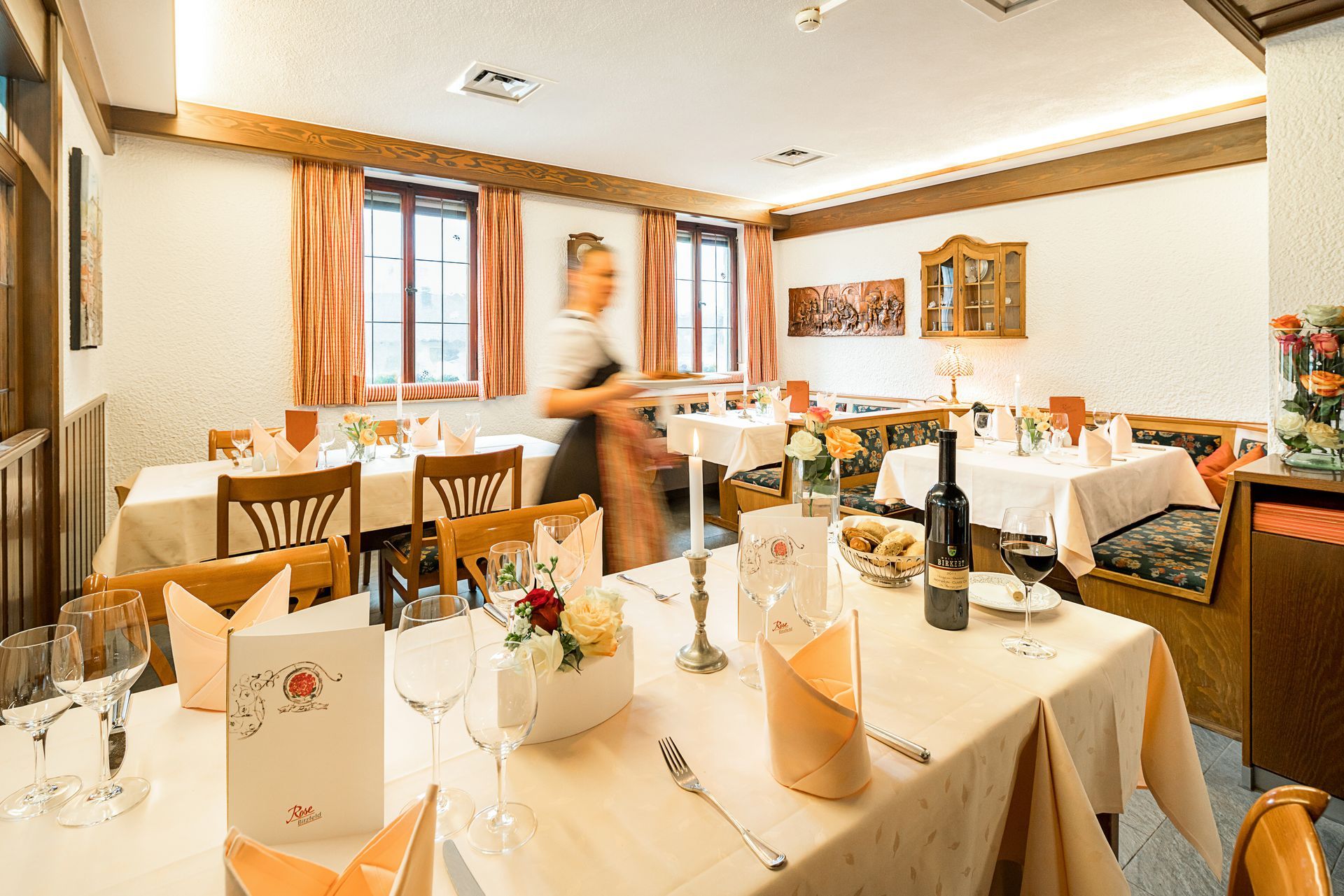 Ein Restaurant mit Tischen und Stühlen und einer Kellnerin, die Essen serviert.
