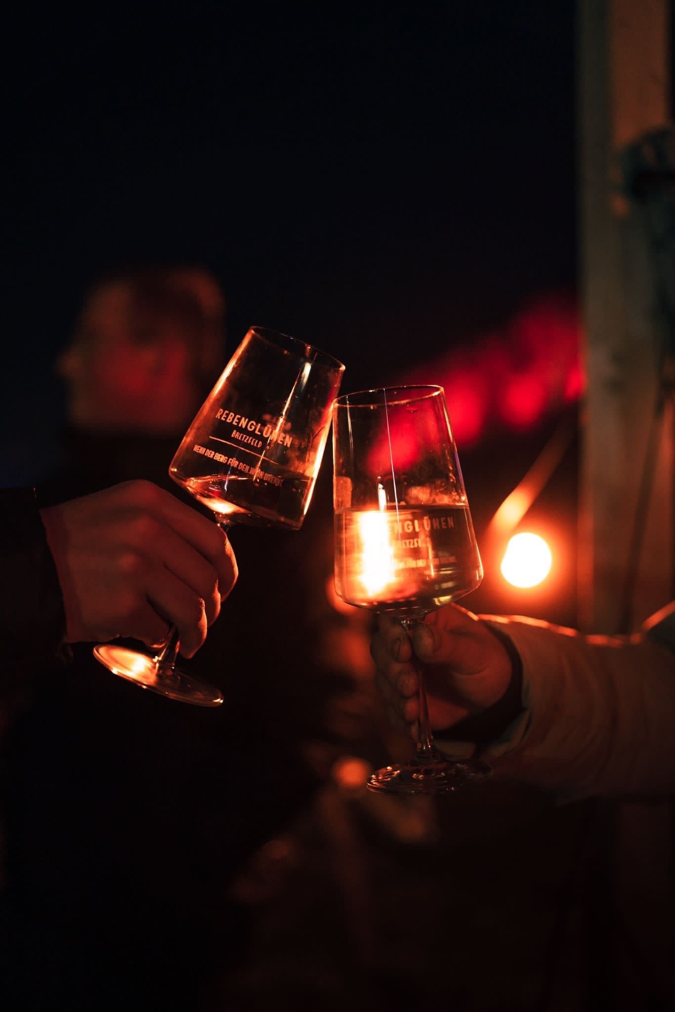 Ein paar Leute stoßen am Abend mit Weingläsern an.