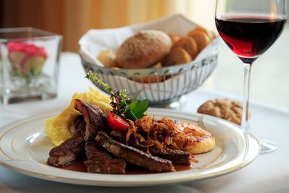 A plate of food and a glass of wine on a table.