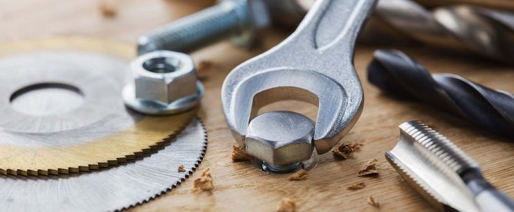 Un primer plano de una llave que sujeta una tuerca sobre una mesa de madera.