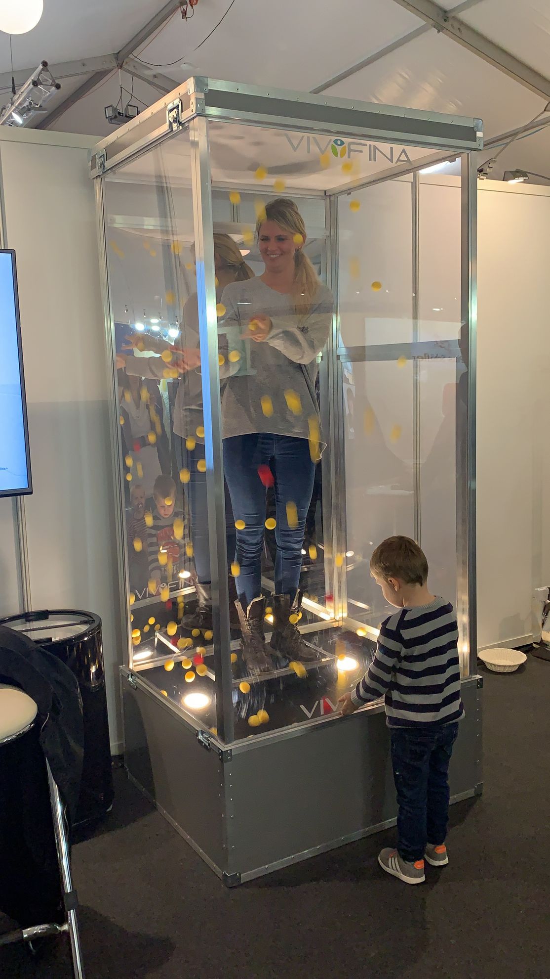 Drei Ansichten einer Glasvitrine mit einer Person darin. Schwarzer Sockel, Beleuchtung und ausgestellte Gegenstände.