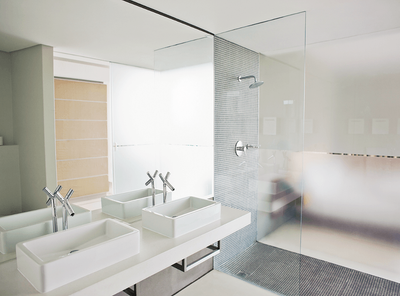 Salle de bains moderne avec double vasque, grand miroir, douche en verre et panneau de fenêtre dépoli.