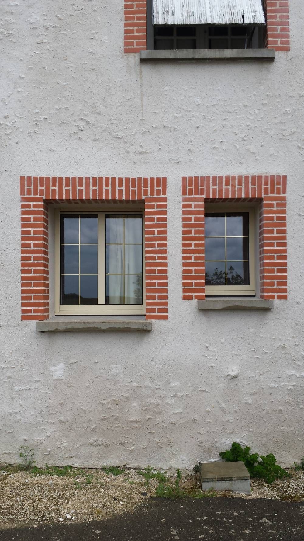Petit mur en stuc blanc avec deux fenêtres encadrées de briques.