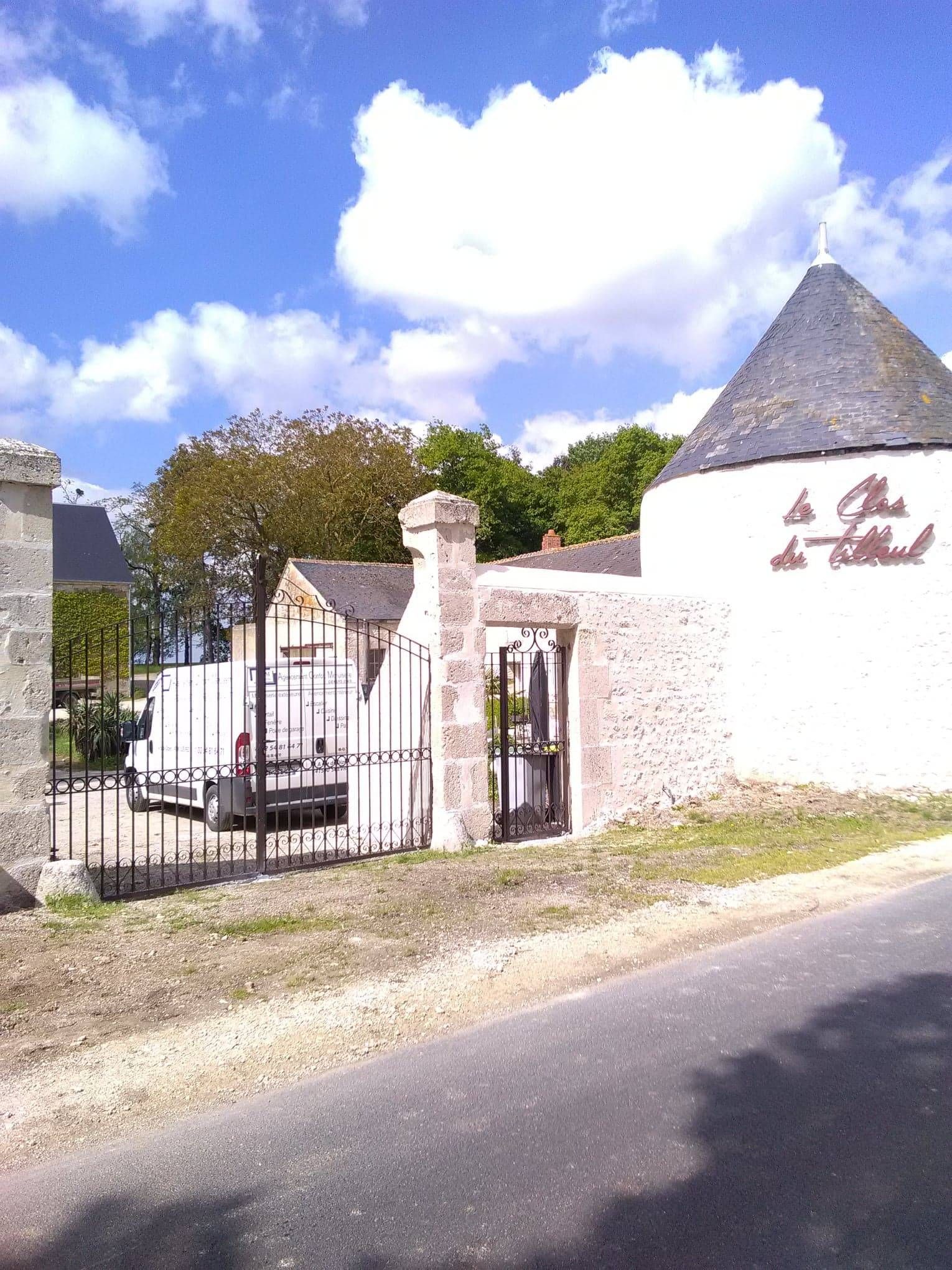 Entrée fermée par un portail aux murs blancs et au toit de chaume.
