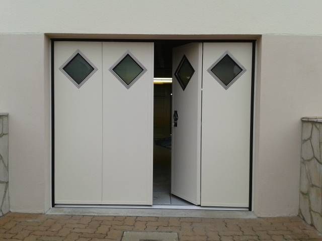 Double porte blanche à fenêtres en losange, l'une des portes étant partiellement ouverte à l'entrée de l'immeuble.
