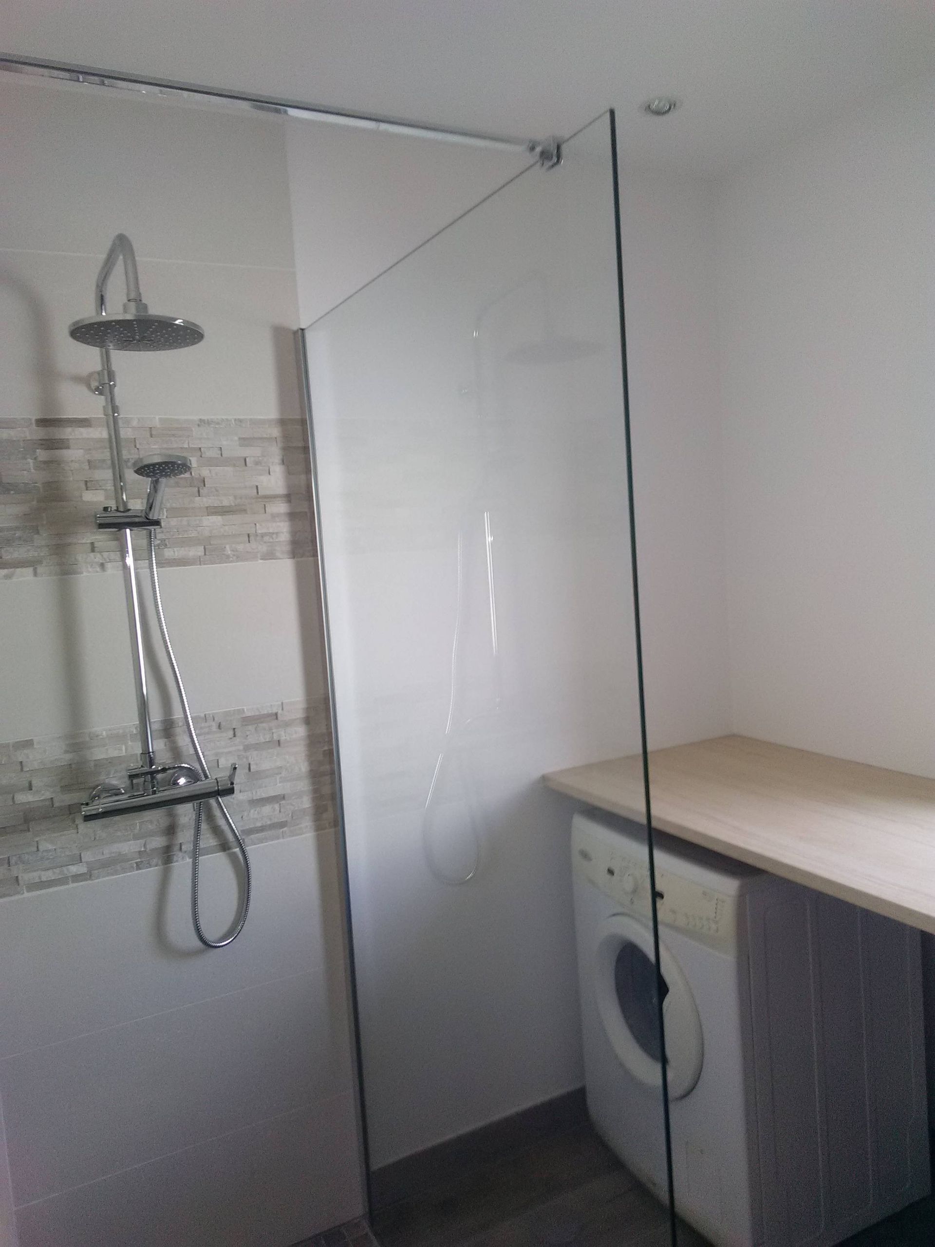 Salle de bains moderne avec douche à l'italienne, paroi de douche en verre et lave-linge sous plan de travail.