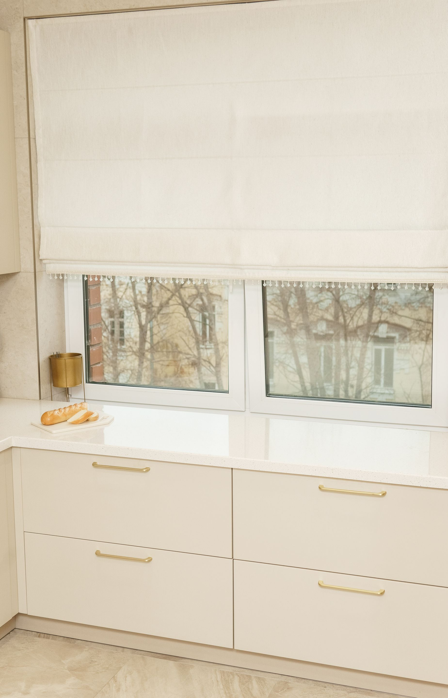 Un store blanc au-dessus d'une banquette-fenêtre avec tiroirs.
