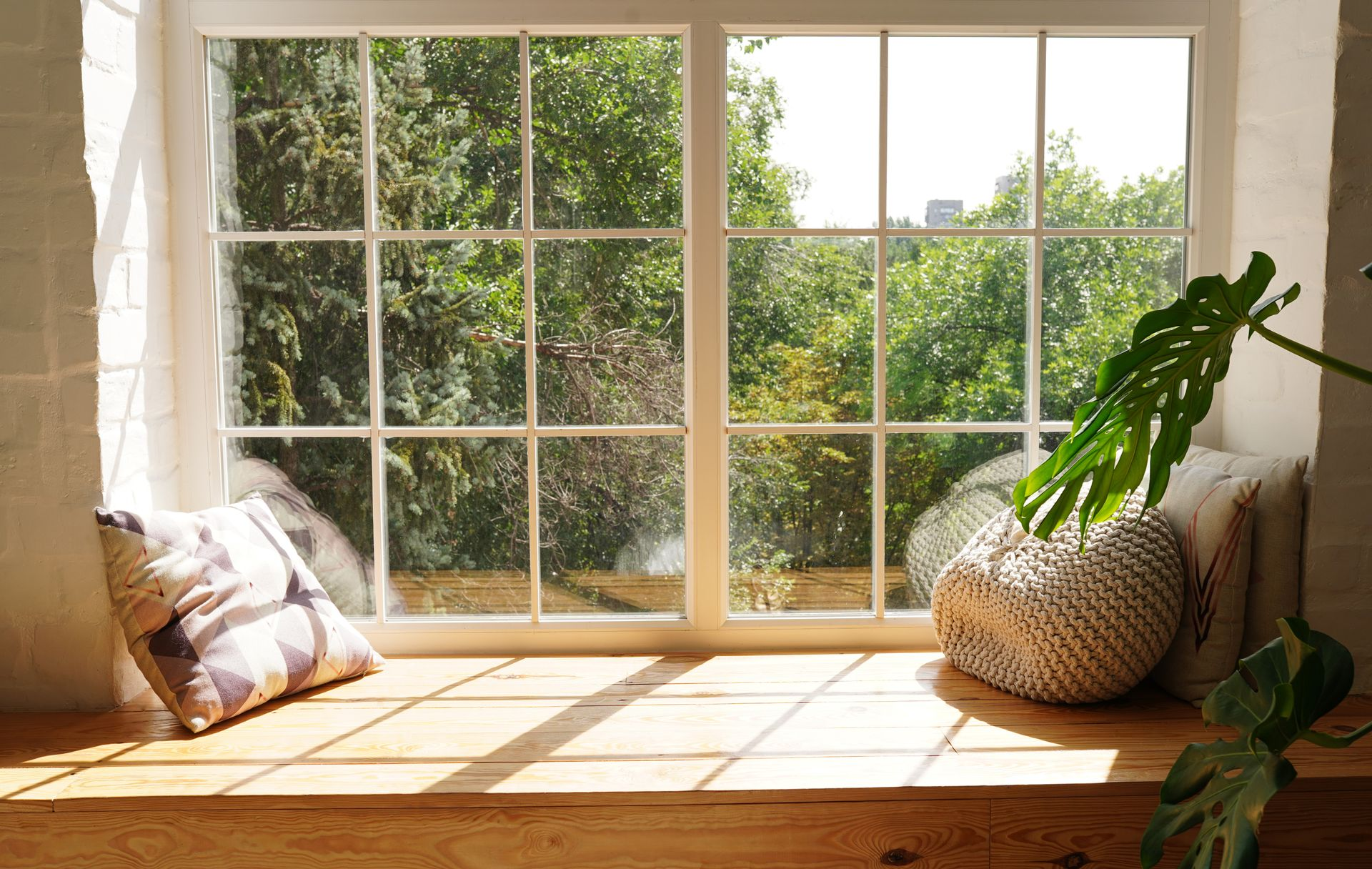 Banquette ensoleillée près de la fenêtre avec coussins et panier à plantes tressé donnant sur le jardin