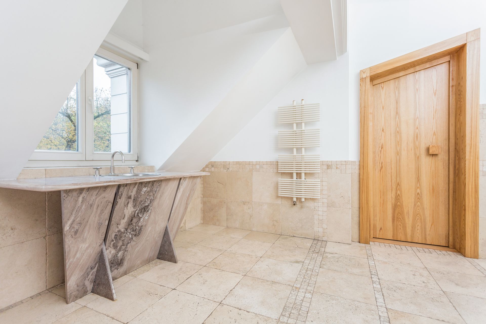 Salle de bains moderne et lumineuse avec carrelage en marbre, fenêtre, porte-serviettes et porte en bois