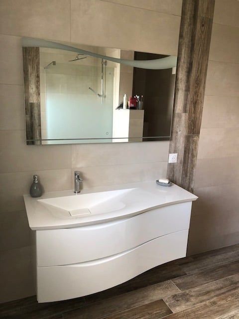 Meuble-lavabo moderne blanc avec tiroirs incurvés, miroir et mur d'accent en bois.