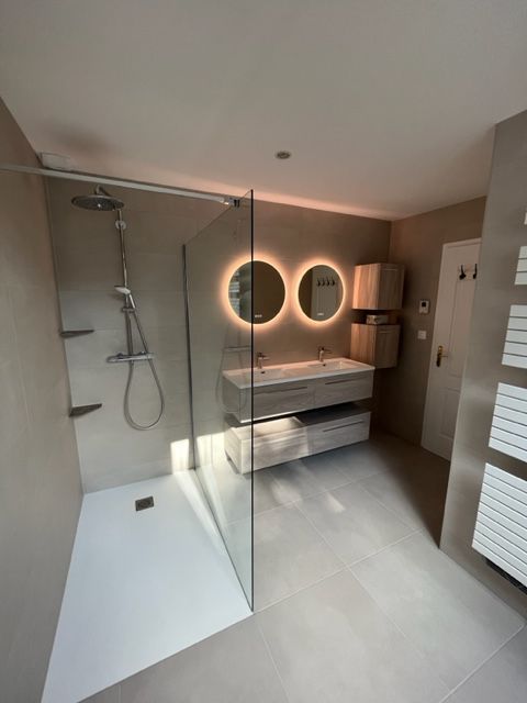 Meuble-lavabo moderne blanc avec tiroirs incurvés, miroir et mur d'accent en bois.