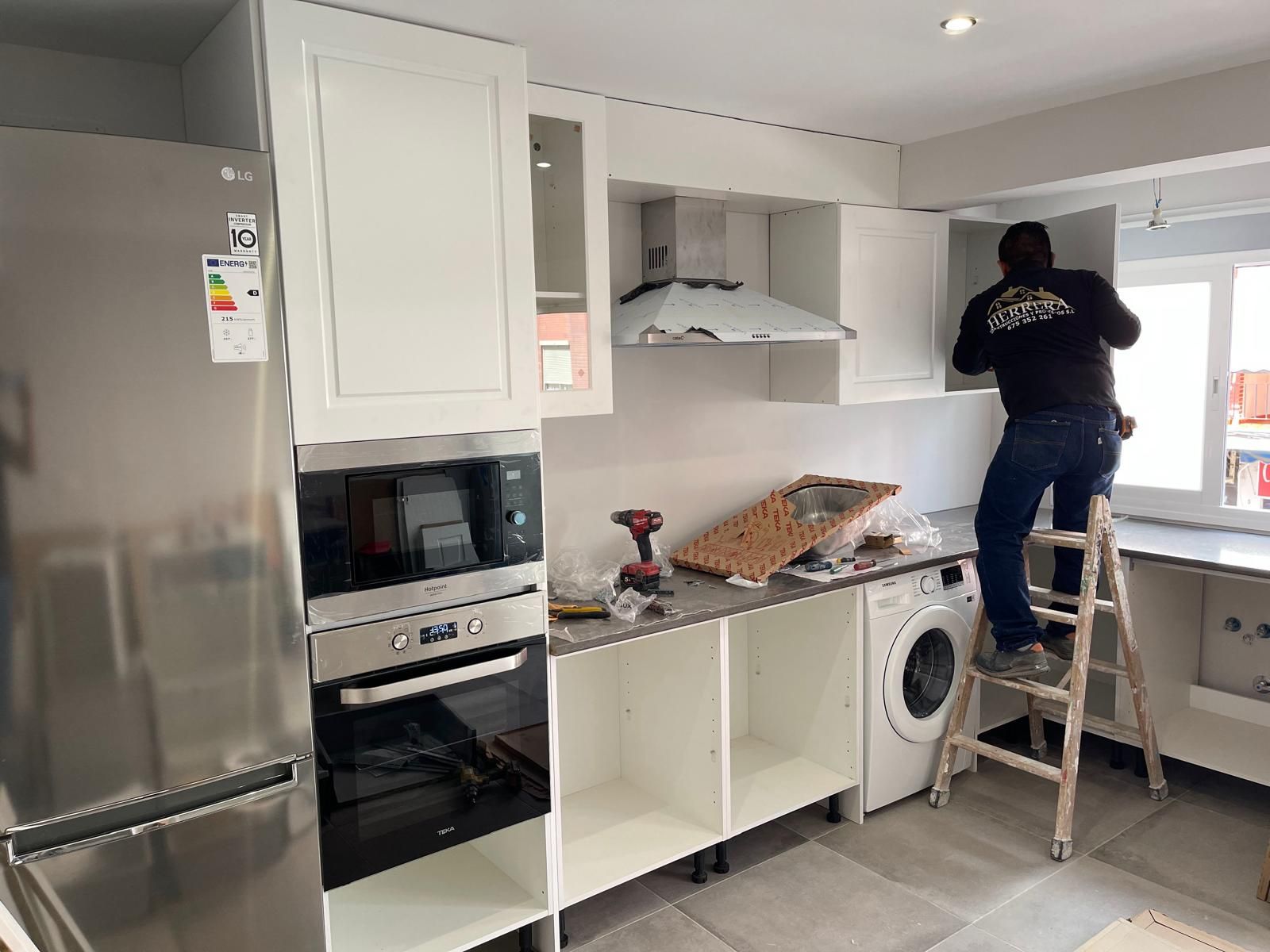 Un hombre está de pie en una escalera en una cocina.