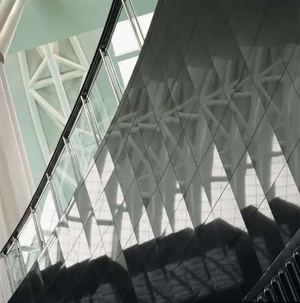 Detalhe arquitetônico: painéis geométricos escuros que refletem uma estrutura de treliça branca.