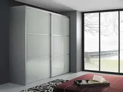 Quarto moderno com guarda-roupa cinza e grande janela com vista para a paisagem.