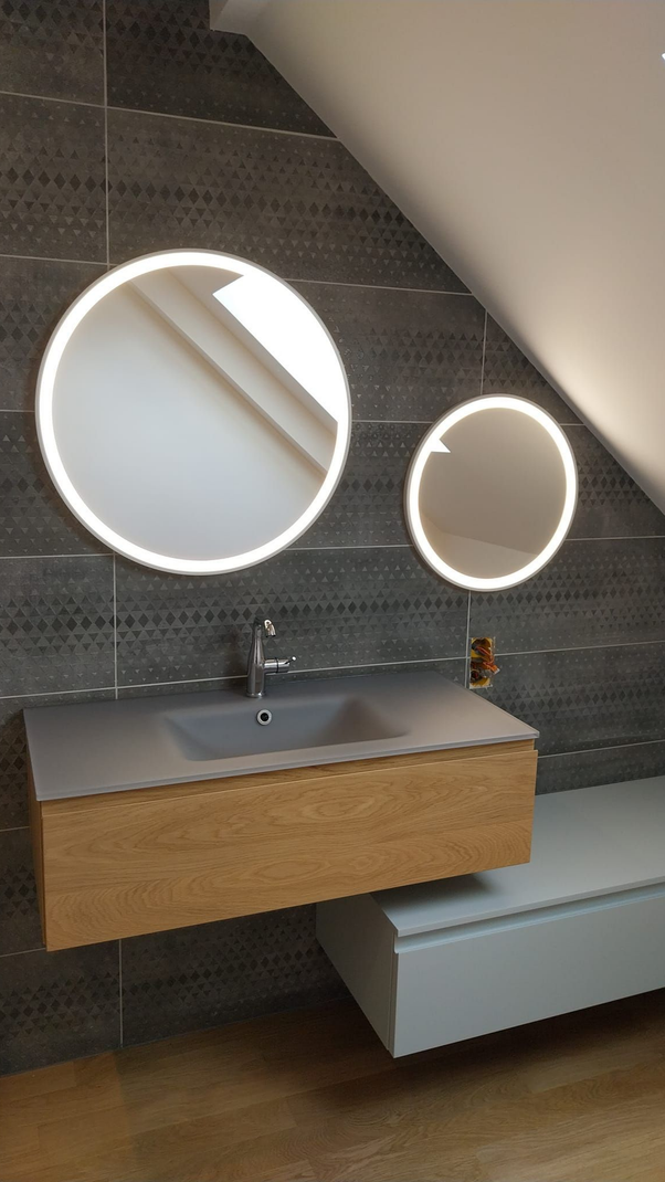 Salle de bains avec vanité flottante en bois, deux miroirs ronds avec lumières