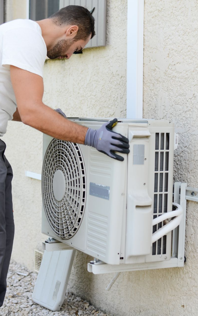 Un homme portant des gants installe une unité de climatisation