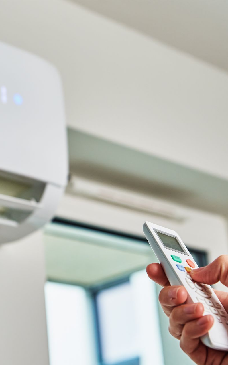 Une personne tenant une télécommande règle le climatiseur