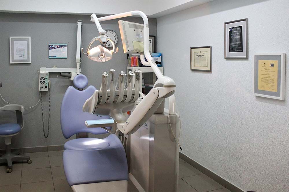 Un consultorio dental con una silla morada y un reloj en la pared.