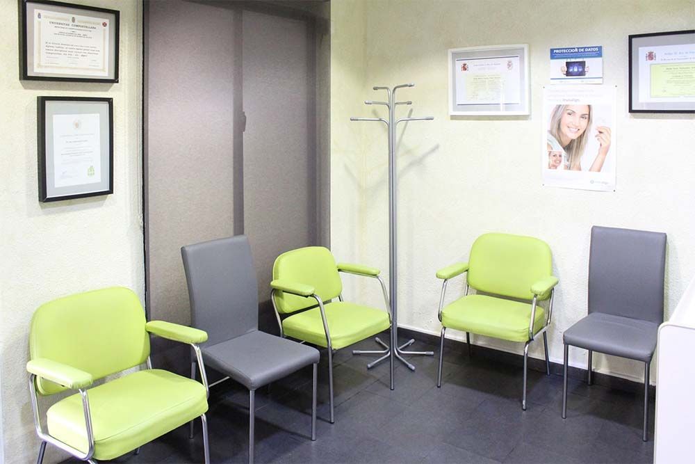 Una sala de espera con sillas verdes y sillas grises.