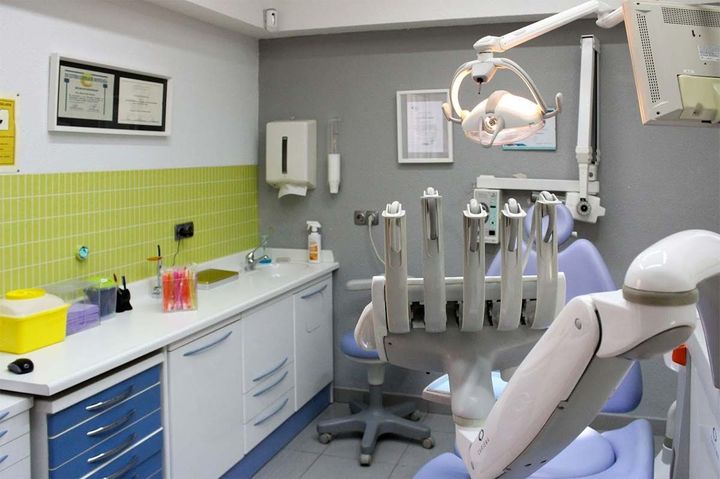 Un consultorio dental con un sillón dental y un lavabo.