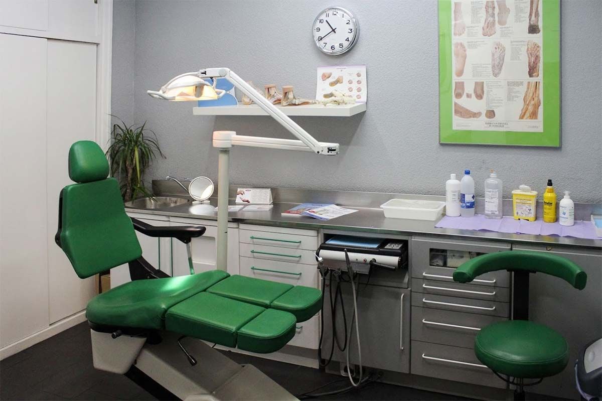 Un consultorio dental con una silla verde y un reloj en la pared.