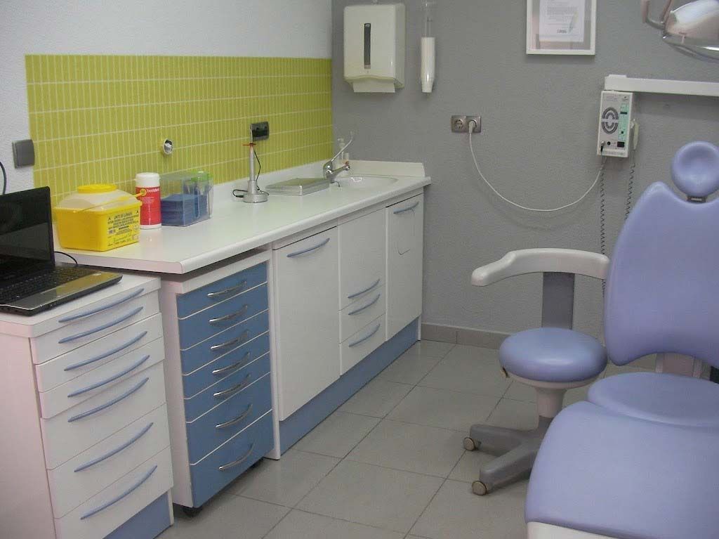 Un consultorio dental con una silla morada y una computadora portátil.