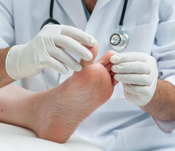 Un médico está examinando el pie de un paciente con un estetoscopio.
