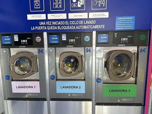 Tres lavadoras están alineadas en una lavandería.