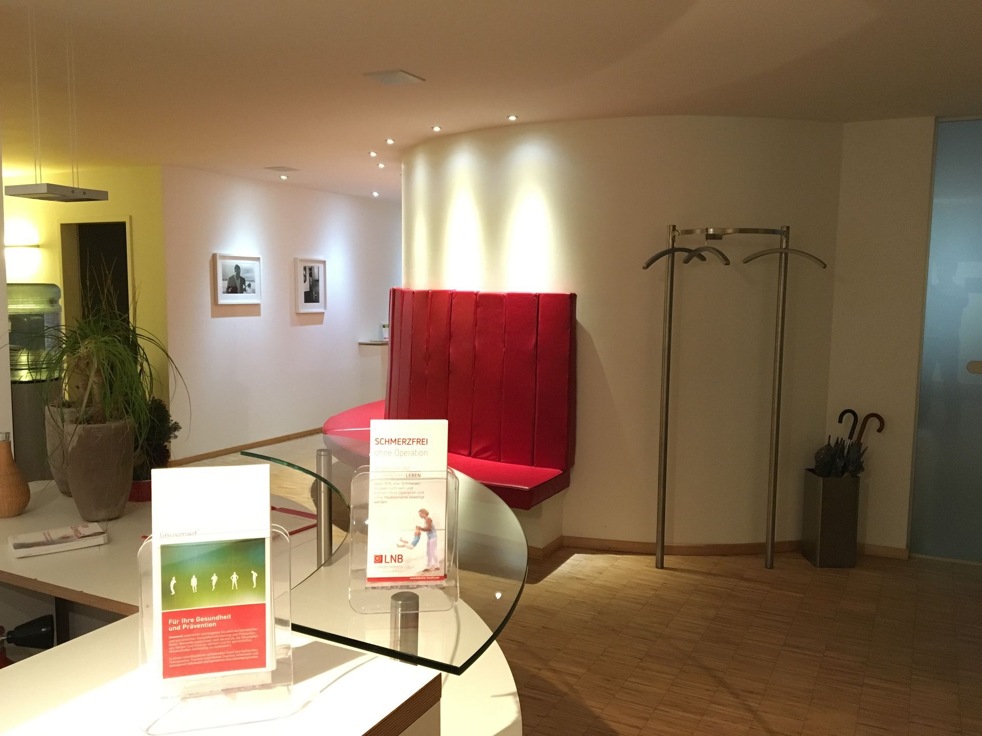 Ein Wartezimmer mit einem Glastisch und einer roten Bank