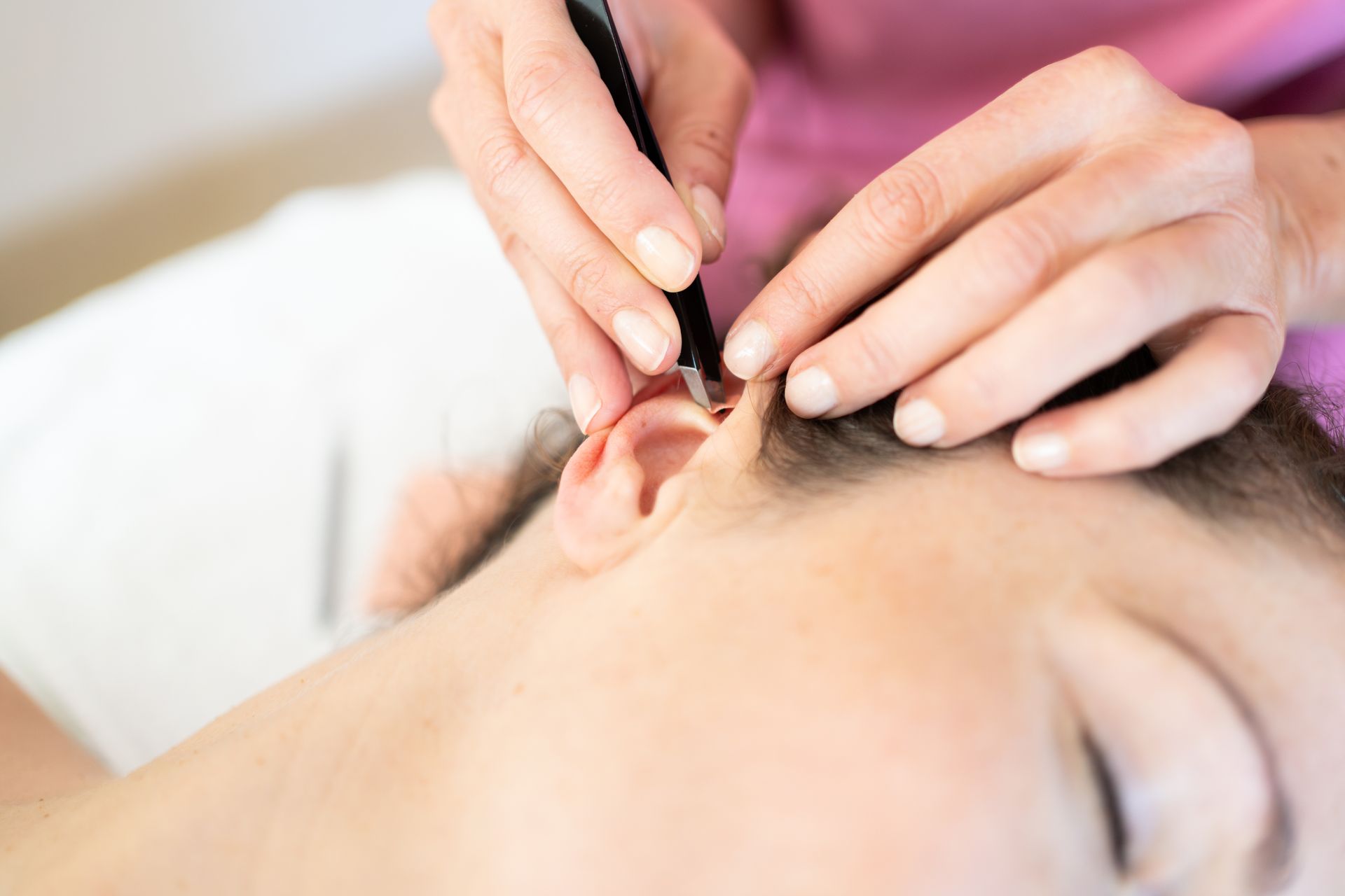 Une personne reçoit un traitement d'acupuncture auriculaire. Une fine aiguille est appliquée sur l'oreille.