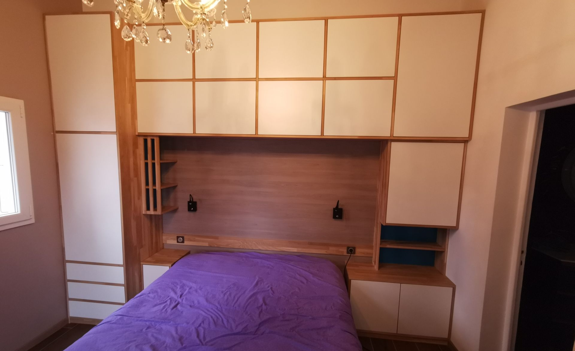 Chambre avec des meubles sur mesure blancs et en bois au-dessus d'un lit violet.