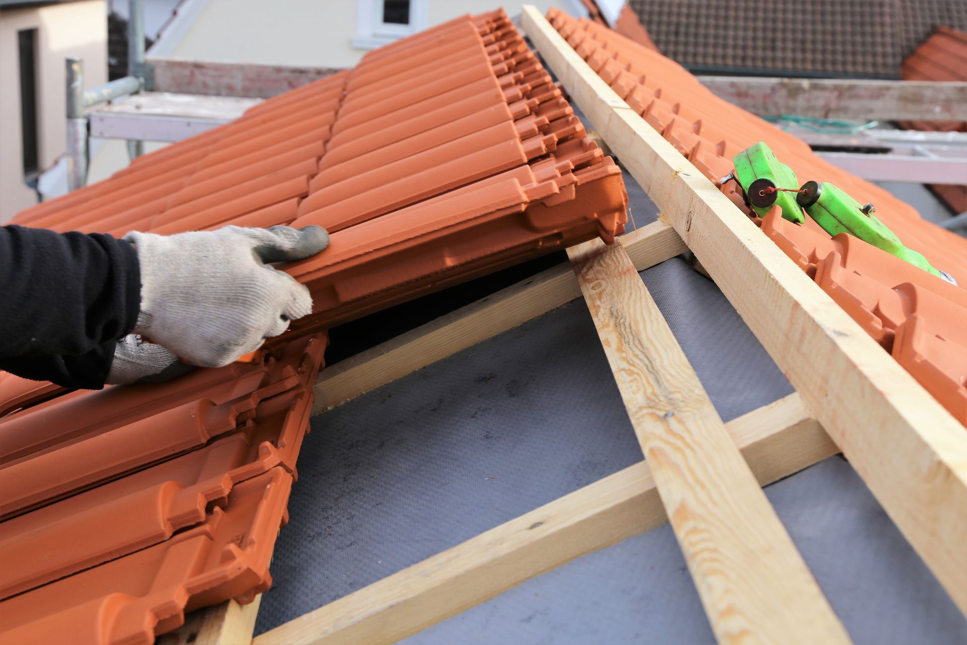 Un couvreur aligne des tuiles rouges sur un toit en construction