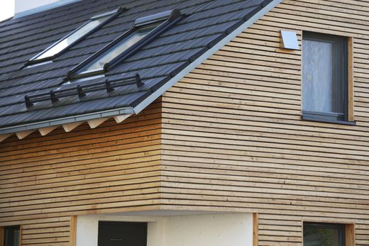 Extérieur de maison moderne avec toit foncé, bardage en bois clair et petite fenêtre