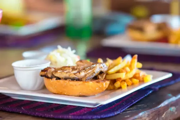 A sandwich and french fries on a plate on a table.