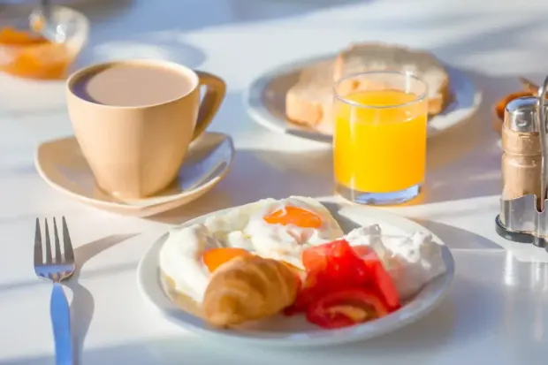 There is a plate of food and a cup of coffee on the table.
