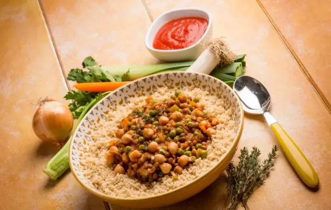 A bowl of food with chickpeas and rice on a wooden table.