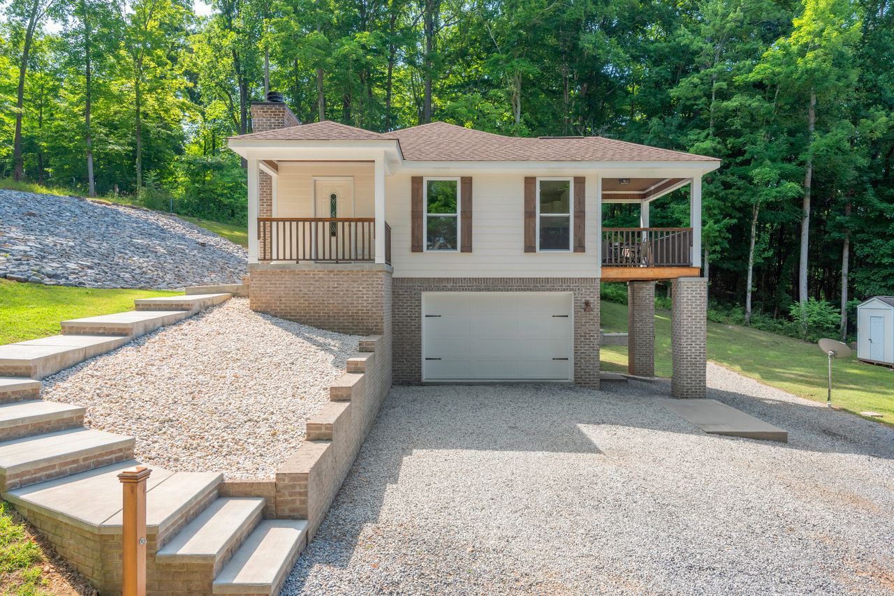 A house with stairs leading up to it and a garage. Norris Lake Rentals