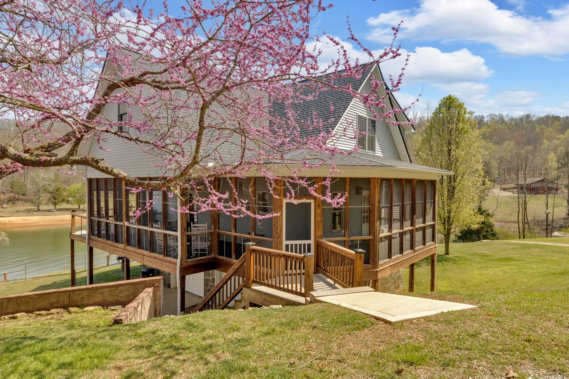 A house with a screened in porch and a lake in the background. Norris Lake Rentals