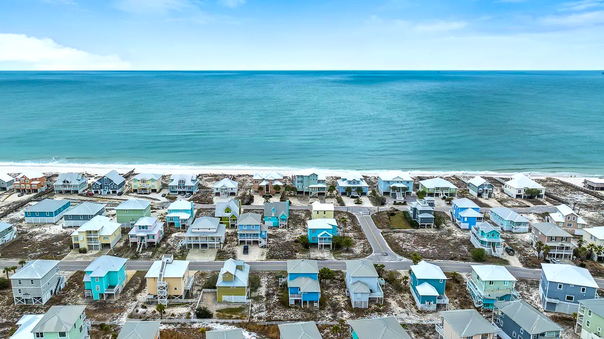 Aerial view of a seaside resort with rows of cabanas and turquoise ocean beyond